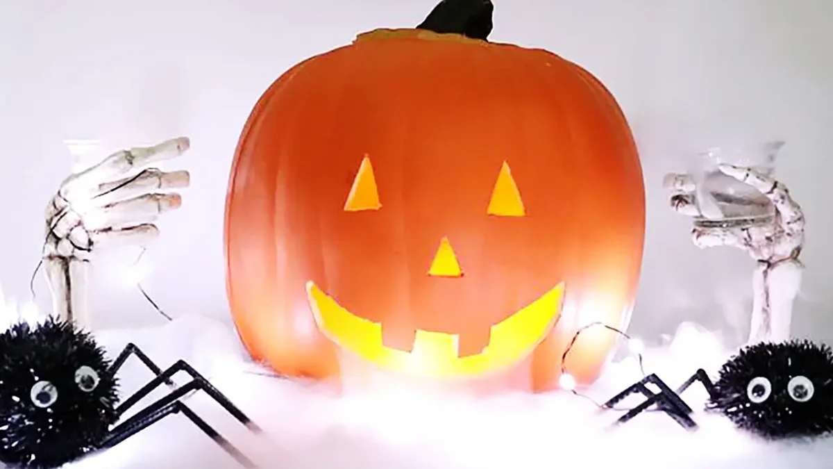 Spooky Jack-o'-lantern centerpiece with skeleton hands holding glasses and spiders.
