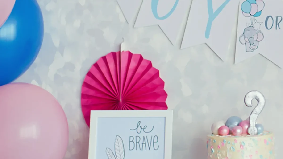Gender reveal party decorations: cake, balloons, "Boy or...?" banner, and "Be Brave" sign.