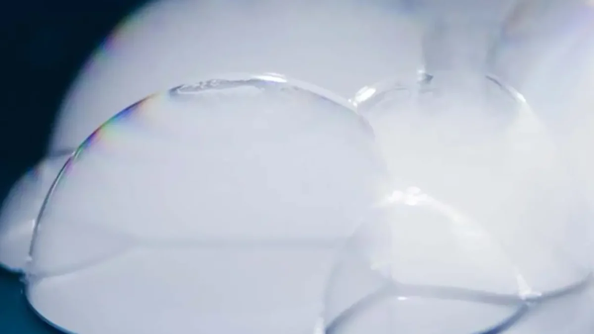 Close-up of ghostly white bubbles, iridescent edges. Science experiment.