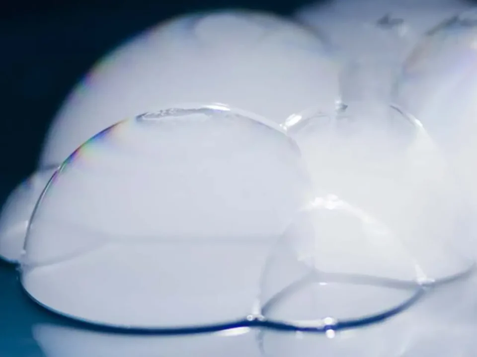 Close-up of ghostly white bubbles, iridescent edges. Science experiment.