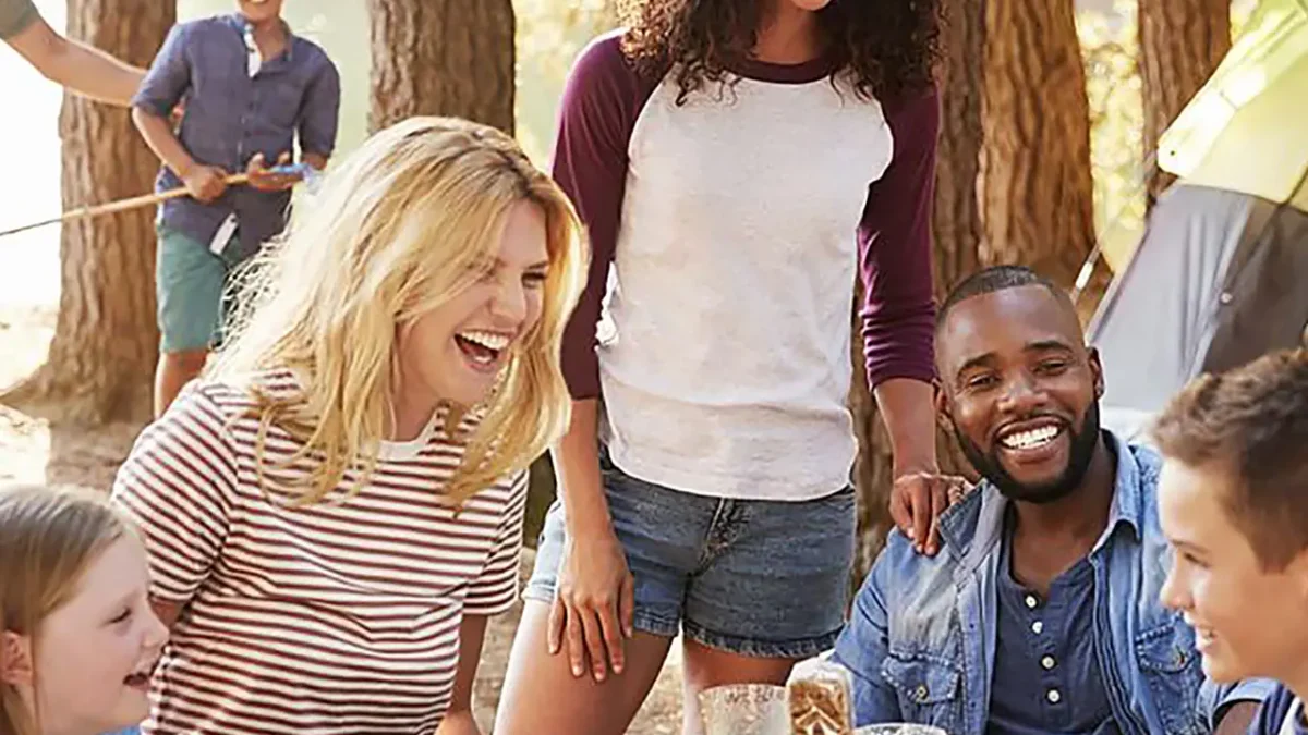 Happy family enjoys a meal at a campsite, using dry ice to keep food cold.