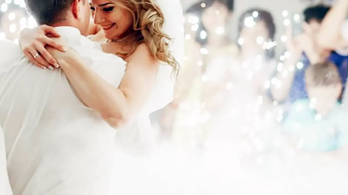 Happy bride and groom embrace during their first dance, surrounded by sparkling dry ice effects.
