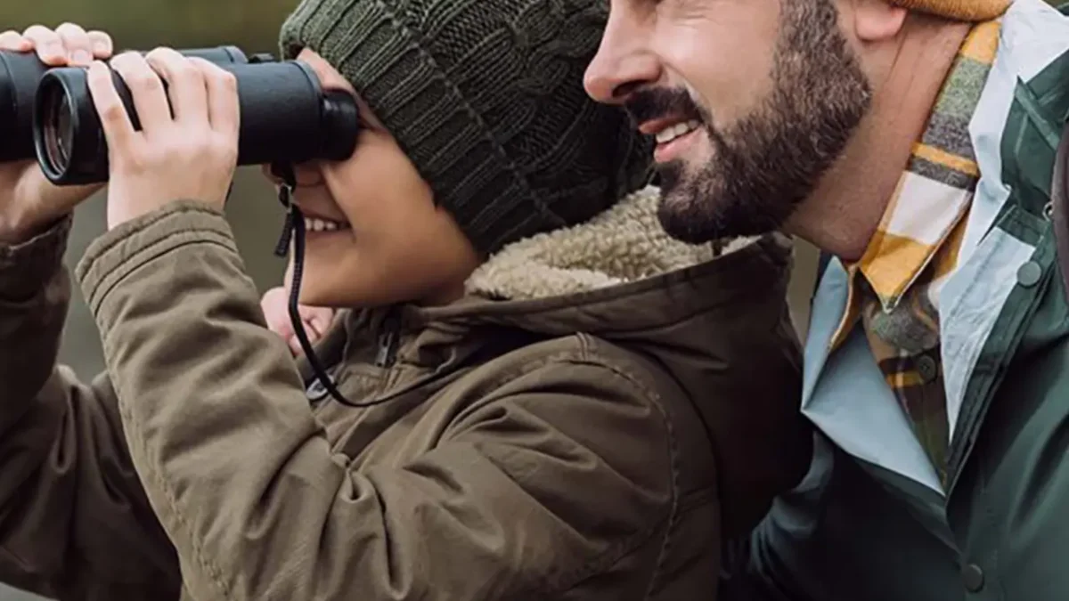 Father and son birdwatching with binoculars.