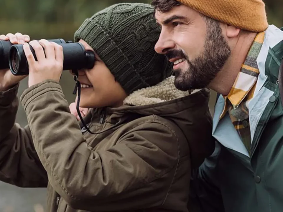 Father and son birdwatching with binoculars.