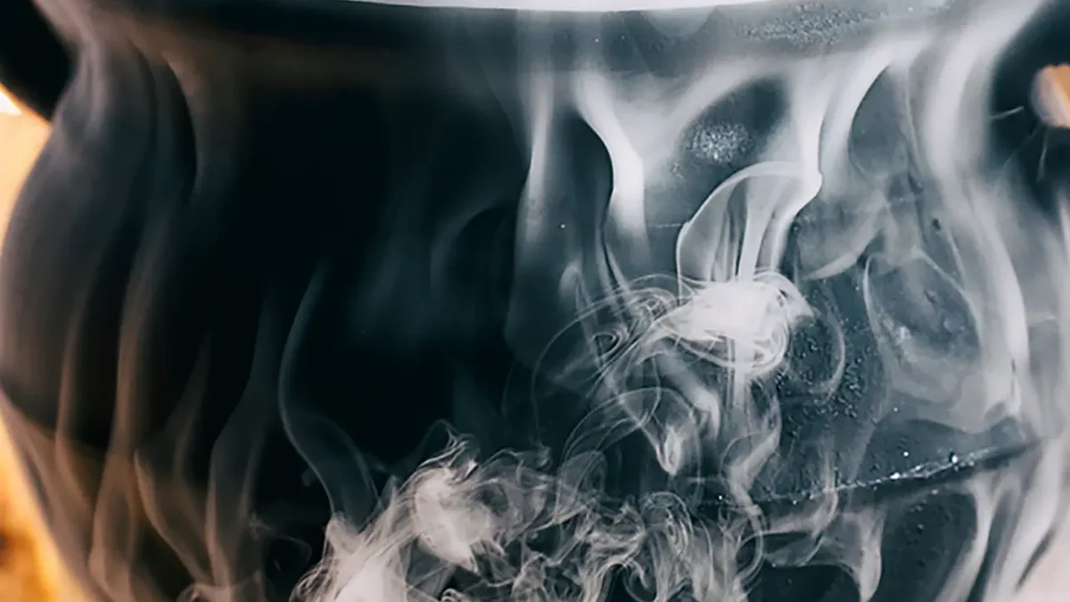 Black cauldron steaming with dry ice, creating long-lasting fog effects.