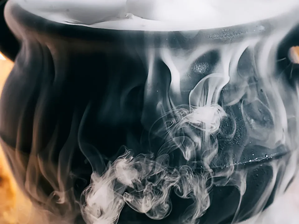 Black cauldron steaming with dry ice, creating long-lasting fog effects.