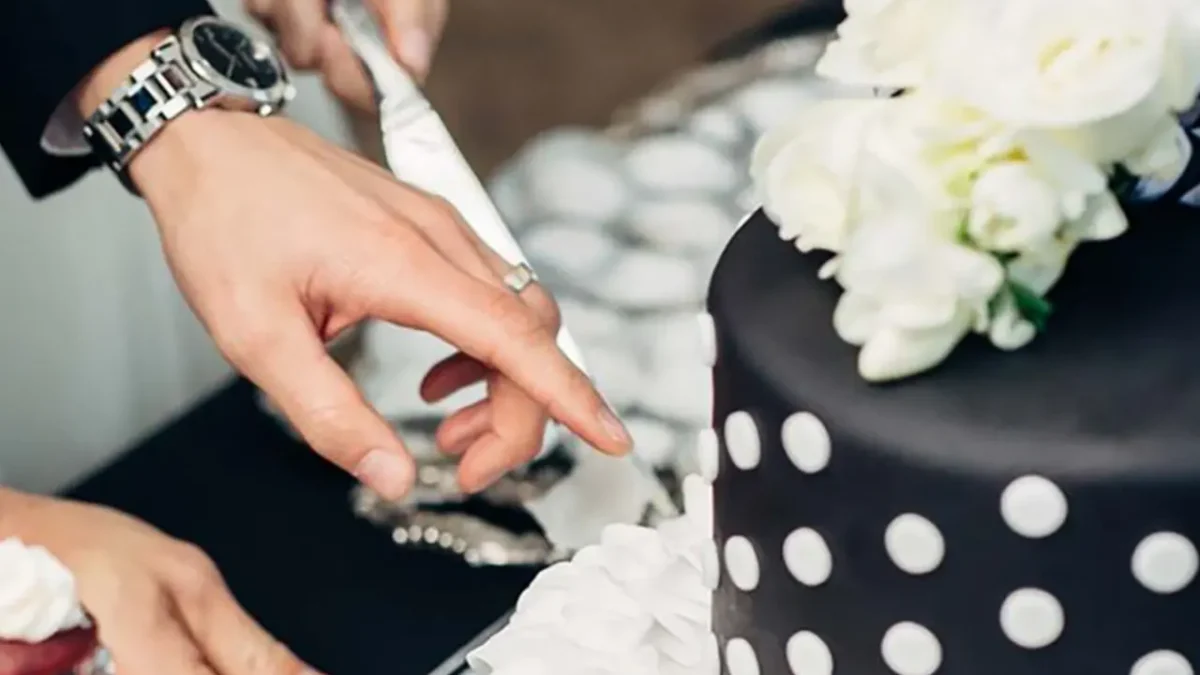 Couple cutting a black and white polka dot wedding cake.