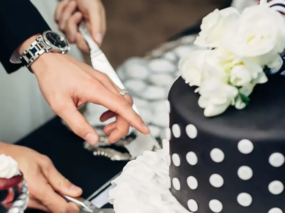 Couple cutting a black and white polka dot wedding cake.