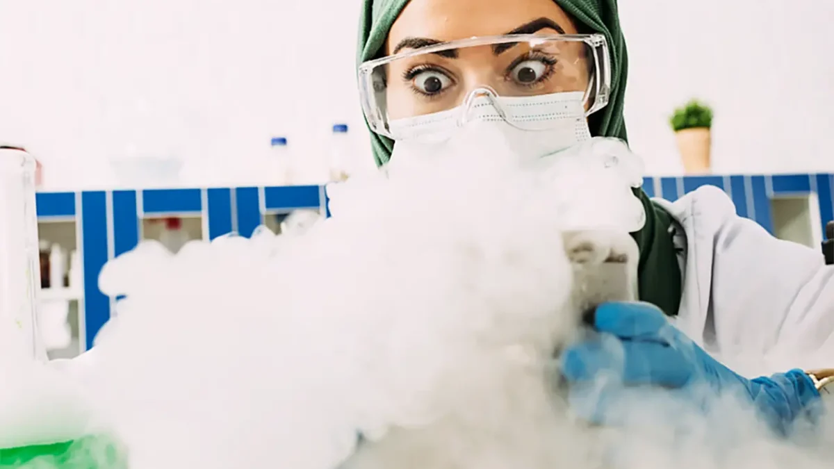Scientist in hijab and safety goggles surprised by dry ice experiment