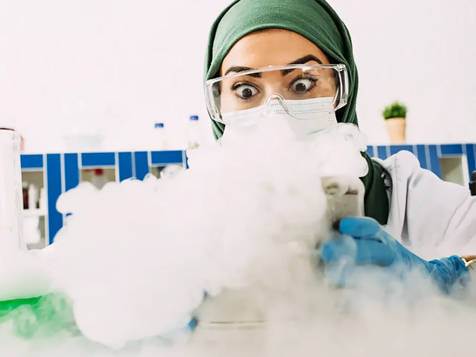 Scientist in hijab and safety goggles surprised by dry ice experiment