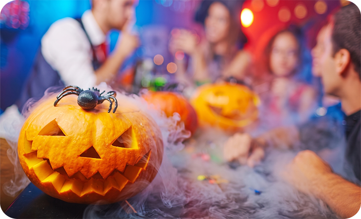 Halloween party scene with Jack-o-lanterns in the forefront and party-goers in the background